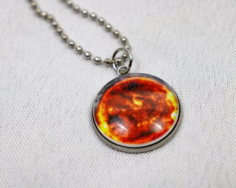 May include: A silver chain necklace with a round pendant featuring a close-up image of the sun.