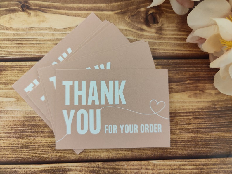 May include: A stack of thank you cards with a light brown background and white text that says "Thank You for your order" with a small heart drawn next to the text.