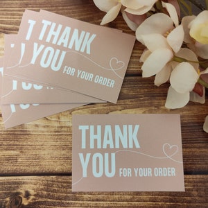 May include: A stack of pink thank you cards with white text that reads "Thank You for your order" and a small heart.