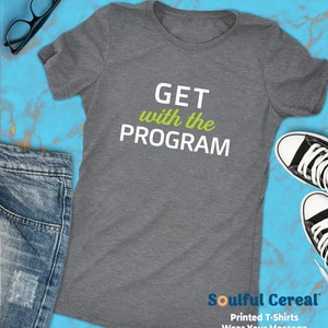 May include: A heather gray t-shirt with the text "GET with the PROGRAM" in white. The word "with" is in green. The t-shirt is on a blue and white background with a pair of jeans and a pair of sneakers.