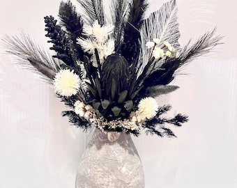 Black & white artificial flowers arranged in a textured ceramic vase,monochrome,modern home decor,protea,pampas grass bouquet arrangement.