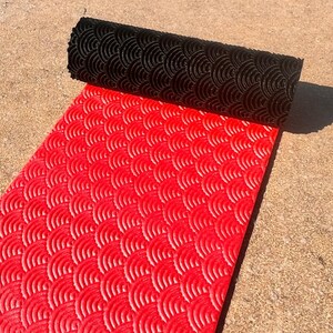 May include: A red and black yoga mat with a wave pattern. The mat is rolled up and the black side is facing the camera.