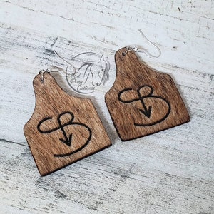 May include: A handmade wooden sign with the text "Welcome" in a playful font. The sign features a distressed white background and a dark stained wooden frame. A small, decorative heart is attached to the bottom.