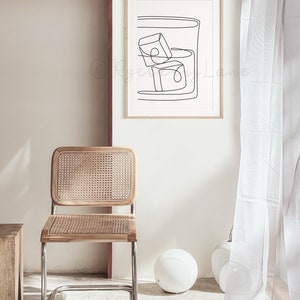 May include: A black and white line drawing of a glass with ice cubes. The drawing is framed and hanging on a white wall.