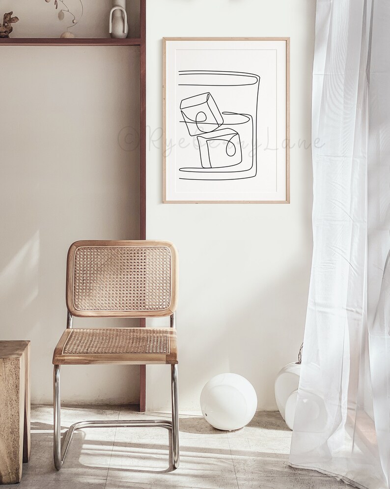 May include: A black and white line drawing of a glass with ice cubes. The drawing is framed and hanging on a white wall.