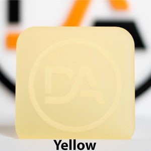 May include: A square, yellow object with rounded corners. The object has a circular logo with the letters "DA" inside. The word "Yellow" is printed at the bottom of the image.