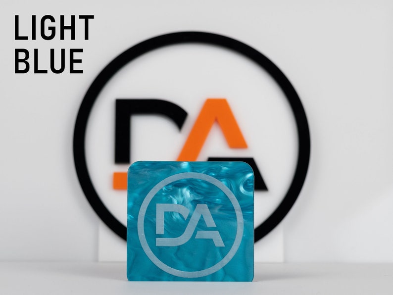 May include: A light blue square acrylic sheet with a white swirl pattern. The sheet has a circular logo with the letters "DA" in white.