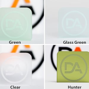 May include: Four square glass blocks in green, glass green, clear, and hunter green. Each block features a circular logo with the letters "DA". The colours are labelled below each block.