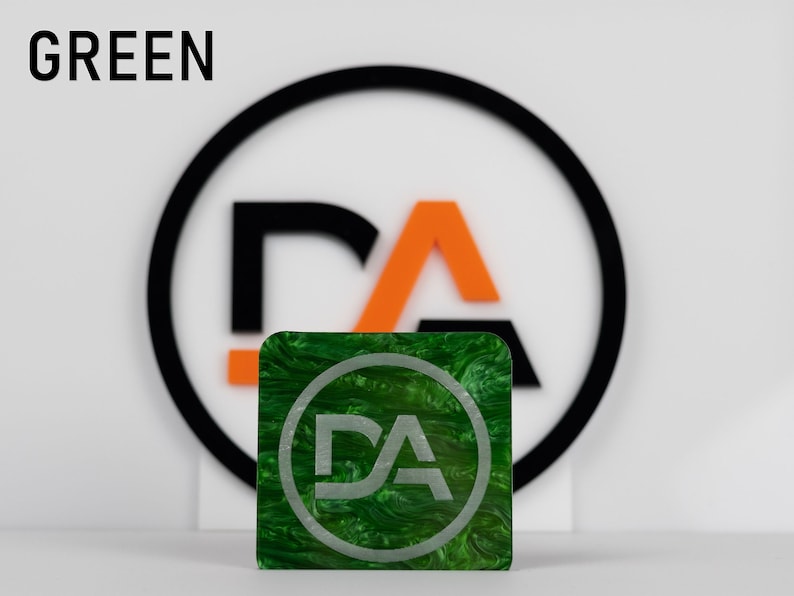 May include: Green square with a swirling pattern and a white circle with the letters "DA" in the center. The square is in front of a black circle with a white "DA" logo inside.