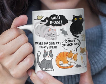 May include: White ceramic mug with a black and white illustration of cats and mice. The mug has text that reads "What mouse?", "Maybe for some cat treats I might", and "Don't touch me".