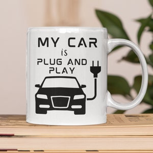 May include: White ceramic mug with a black graphic of a car plugged in with the text "My car is plug and play".