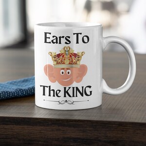 Ceramic mug, 11oz, displaying a charming cartoon king Charles with big ears, and text 'Ears to the King' wearing a richly detailed crown, perfect gift for the Royal family lovers with a sense of humour!