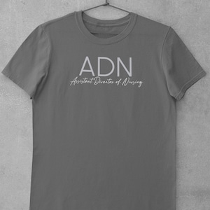 May include: A dark gray t-shirt with the text "ADN Assistant Director of Nursing" printed in white.