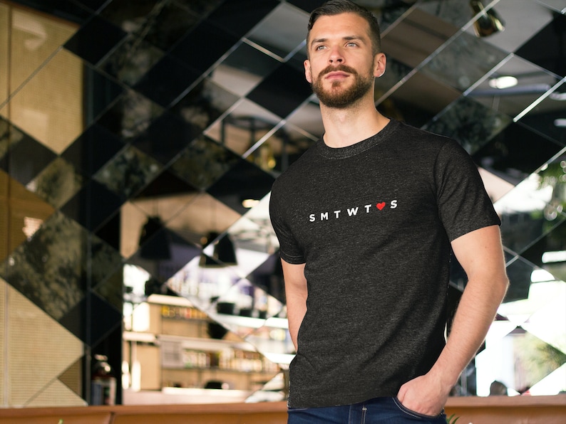 May include: A dark gray t-shirt with a white graphic that says "SMTWTFS" with a red heart in place of the "O".