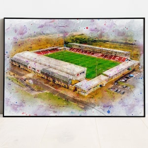 Peut inclure: Une peinture à l'aquarelle d'un stade de football avec un terrain vert et des tribunes rouges et blanches. Le stade est entouré d'un parking et d'arbres.