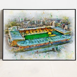 以下が含まれることがあります： 緑のフィールドと黄色の座席があるスタジアムの水彩画風プリント。 「NORWICH CITY」の文字が見えます。 アートワークは黒いフレームで額装されており、カラフルなペイントスプラッターが特徴です。