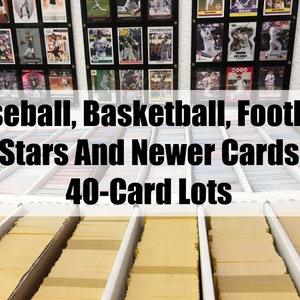 May include: A collection of baseball, basketball, and football trading cards organized in rows of 40-card lots. The cards are displayed in clear plastic sleeves and are arranged in a white storage box.