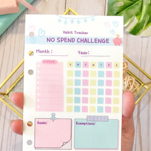 May include: A printable habit tracker with a pink piggy bank illustration and the text "No Spend Challenge". The tracker includes sections for month, year, notes, goals, exemptions, and a calendar grid with days of the week labelled S, M, T, W, T, F, S. The tracker also features a pink and blue colour scheme with hearts and a banner that reads "Small Habits Big Changes" and "Little Potato Saver".