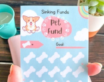 May include: A blue and pink printable tracker for saving money for a pet fund. The tracker features a cartoon corgi, a bone, and the text "Sinking Funds Pet Fund Goal:".