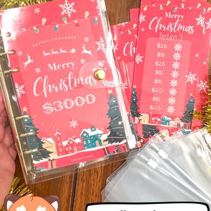 Pode incluir: Uma pasta de pl&aacute;stico transparente com uma capa vermelha e branca com tema natalino. A capa tem o texto "Feliz Natal 3000 &euro;" e uma pequena ilustra&ccedil;&atilde;o de uma &aacute;rvore de Natal e casas. A pasta est&aacute; aberta para revelar uma p&aacute;gina com um rastreador de desafio de poupan&ccedil;a. H&aacute; tamb&eacute;m v&aacute;rios cart&otilde;es vermelhos e brancos com tema natalino com o texto "Feliz Natal Se&ccedil;&atilde;o 3" e uma lista de quantias em euros. Os cart&otilde;es est&atilde;o em um envelope de pl&aacute;stico transparente. A imagem tamb&eacute;m inclui um pequeno personagem de desenho animado de panda vermelho com um bal&atilde;o de fala que diz "Conjunto completo de pastas! Rastreadores + Envelopes + Pasta!!"