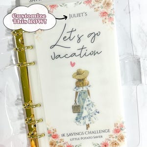May include: A clear binder with gold rings and a decorative insert. The insert features the text "Let's go vacation" and a drawing of a woman in a dress and hat. Floral accents and the text "1K Savings Challenge" are also present.