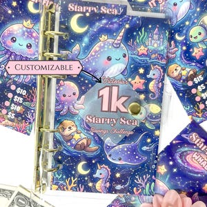 Peut inclure: Un classeur A6 en plastique transparent avec des anneaux dorés sur le thème Starry Sea. La couverture présente un narval, une pieuvre, une loutre et une raie avec le texte Victoria's 1k Starry Sea Savings Challenge et une étiquette personnalisable.