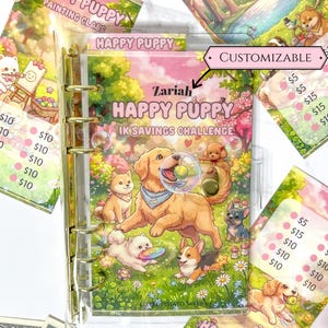 May include: A clear plastic binder with gold rings featuring a Zariah Happy Puppy 1K Savings Challenge cover. The cover displays a golden retriever, a corgi, and other puppies in a park with bubbles, flowers, and text. Includes matching inserts.