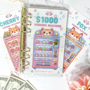 Peut inclure: Un classeur en plastique transparent avec des anneaux dorés contenant un insert de suivi d'épargne Vending Machine à 1000 $. L'insert présente un graphique coloré de distributeur automatique avec un chat, des collations, des boissons et le texte Little Potato Saver.