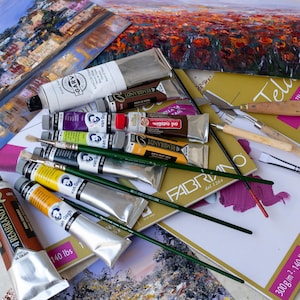 May include: A collection of oil paint tubes from brands including Rembrandt, Van Gogh, and Garv, alongside several paintbrushes with green handles, a palette knife, and a pad of Fabriano canvas paper featuring a 300 g/m2 and 140 lbs label.