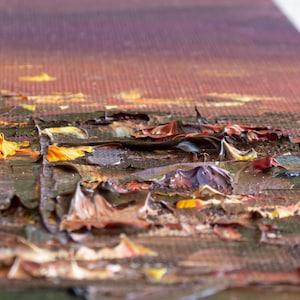 May include: An oil painting on canvas featuring a textured impasto technique with thick, raised layers of paint. The color palette includes deep shades of brown, dark red, and black, accented by vibrant streaks of bright yellow and orange paint.