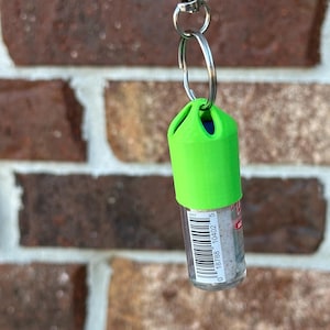 Peut inclure: Un porte-cl&eacute;s vert avec une bouteille en plastique transparente attach&eacute;e. La bouteille a un code-barres qui indique "0 18788 10402 5".