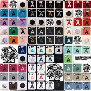 Op de afbeelding: Een raster van kleine, vierkante kleurstalen met de letter "A" en kleurnamen. De kleuren omvatten roze, blauw en groen. De afbeelding bevat ook een logo met een beerachtig wezen en de tekst "OSQ AMAZING".
