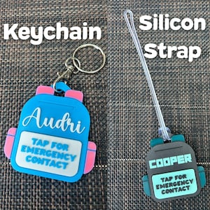 May include: Two personalized backpack-shaped tags. One is a keychain, blue with pink accents, the name "Audri", and the text "Tap for Emergency Contact". The other is a silicon strap tag, black with teal accents, the name "Cooper", and the same text.