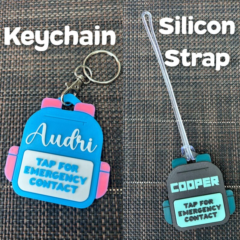 May include: Two personalized backpack-shaped tags. One is a keychain, blue with pink accents, the name "Audri", and the text "Tap for Emergency Contact". The other is a silicon strap tag, black with teal accents, the name "Cooper", and the same text.