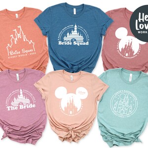 May include: Five t-shirts with a Disney theme. The shirts are in various colors, including pink, blue, and green. The shirts feature a white outline of Cinderella's castle with text that says "Bride Squad", "The Bride", and "Sarah's Bachelorette".