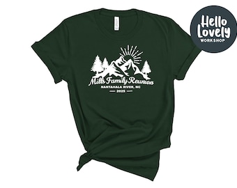 May include: A dark green t-shirt with a white graphic design of mountains, trees, and a sun. The text on the shirt reads "Mills Family Reunion - Nantahala River, NC - 2023".