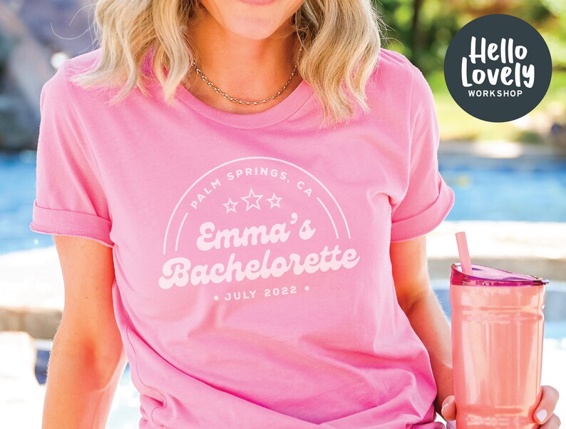 Puede incluir: Camiseta rosa con un gr&aacute;fico blanco de estilo retro que dice "Palm Springs, CA" con tres estrellas y "Emma's Bachelorette" con la fecha "Julio 2022".