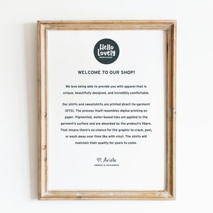 May include: A framed print with the text "Hello Lovely Workshop" and "Welcome to Our Shop!" The text describes the apparel as unique, beautifully designed, and comfortable. The print is in a light brown wooden frame.
