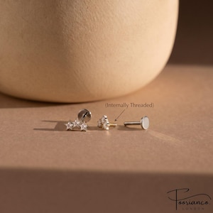 Op de afbeelding: Een zilverkleurige labret-stud met een cluster van drie kleine, heldere, stervormige steentjes. Het sieraad is intern voorzien van schroefdraad en toont een platte, ronde achterkant en een losse staaf. De tekst Internally Threaded is zichtbaar.