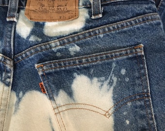 May include: A pair of blue denim jeans with a bleached effect. The back pocket has a Levi's patch with the text "Levi Strauss & Co. Original  Quality Clothing" and the numbers "42505 0216 W34 L32".