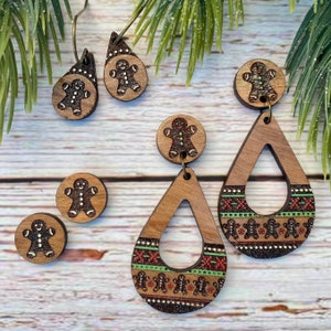 Puede incluir: Un par de pendientes de madera de hombre de jengibre con un diseño de patrón verde y rojo. Los pendientes tienen forma de lágrima y tienen un dije de hombre de jengibre colgando de la parte superior.