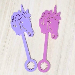 May include: Two purple and pink unicorn head shaped wooden stick toys with a flower design at the bottom.