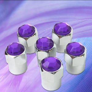 May include: Six purple rhinestone tire valve stem caps. The caps are silver with a hexagonal base and a purple rhinestone on top.