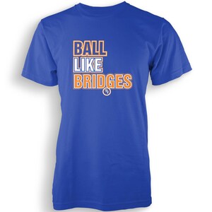 Könnte beinhalten: Königsblaues T-Shirt mit dem Text "BALL LIKE BRIDGES" in Orange und Weiß. Das Shirt hat einen Rundhalsausschnitt und kurze Ärmel. Der Text ist gestapelt, mit "BALL" über "LIKE" über "BRIDGES".