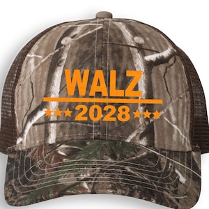 May include: Camouflage trucker hat with the word "WALZ" in orange block letters above the number "2028" and five orange stars. The hat has a brown mesh back and a curved brim.
