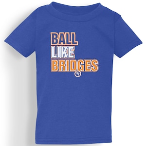 Könnte beinhalten: Königsblaues T-Shirt mit dem Text "BALL LIKE BRIDGES" in weißen und orangefarbenen Blockbuchstaben. Das Shirt hat kurze Ärmel und einen Rundhalsausschnitt. Unter dem Text befindet sich ein kleines Logo.