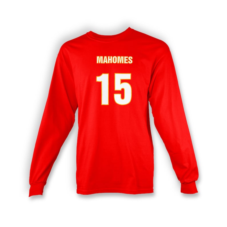 Op de afbeelding: Rood T-shirt met lange mouwen met de naam "Mahomes" en het nummer "15" gedrukt in wit met een gele omtrek.