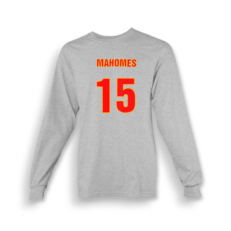 Op de afbeelding: Een grijs longsleeve t-shirt met de naam "MAHOMES" en het nummer "15" gedrukt op de rug in rood met een gele omtrek.