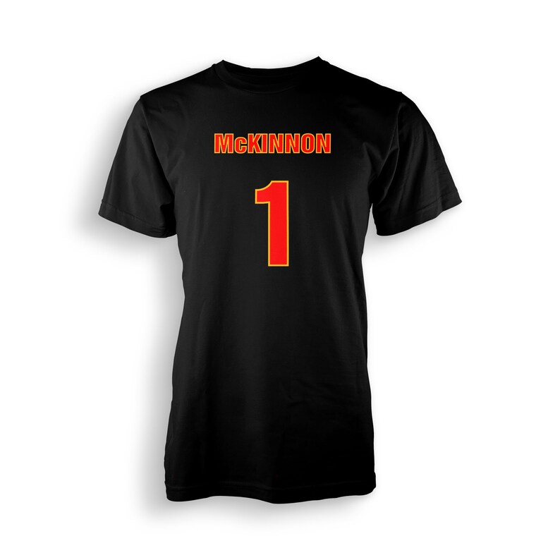 以下が含まれることがあります： 黒地に「MCKINNON」と「1」の文字が入ったTシャツ。数字の「1」は赤色で、黄色い縁取りがされている。