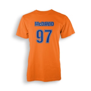 May include: Orange t-shirt with the name "McDavid" and the number "97" printed in blue.